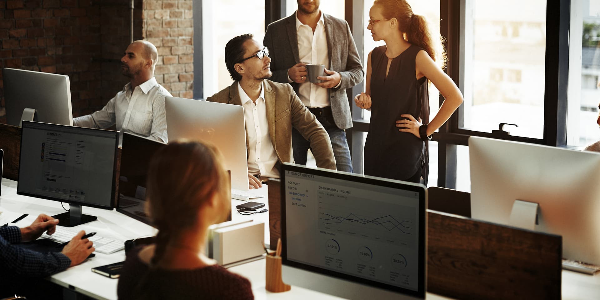 A sales team collaborating around monitors in a modern office